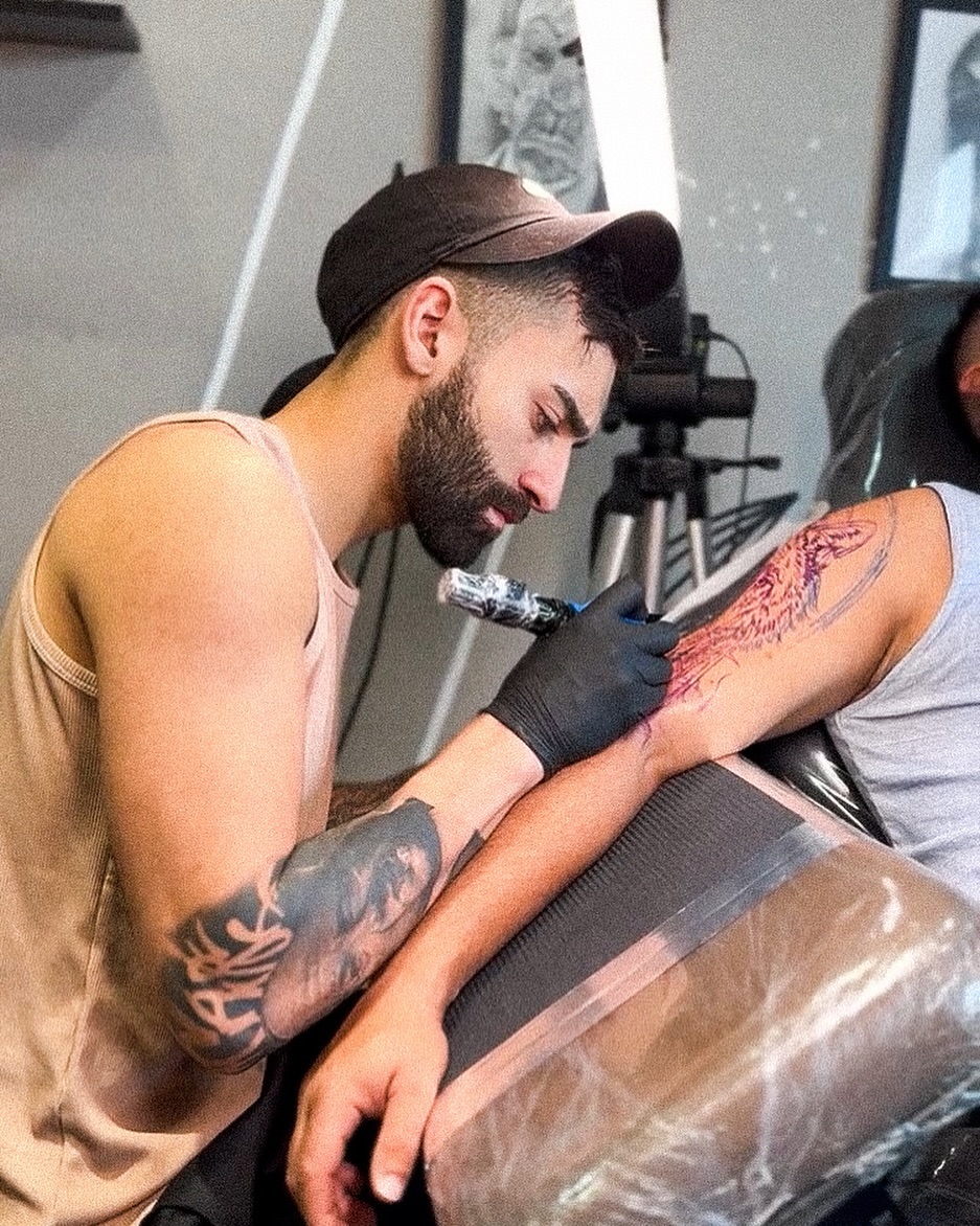 Tatuador fazendo uma tatuagem no braço de um cliente. Nome do tatuador: Jamaica. instagram @jamaica.tattoo